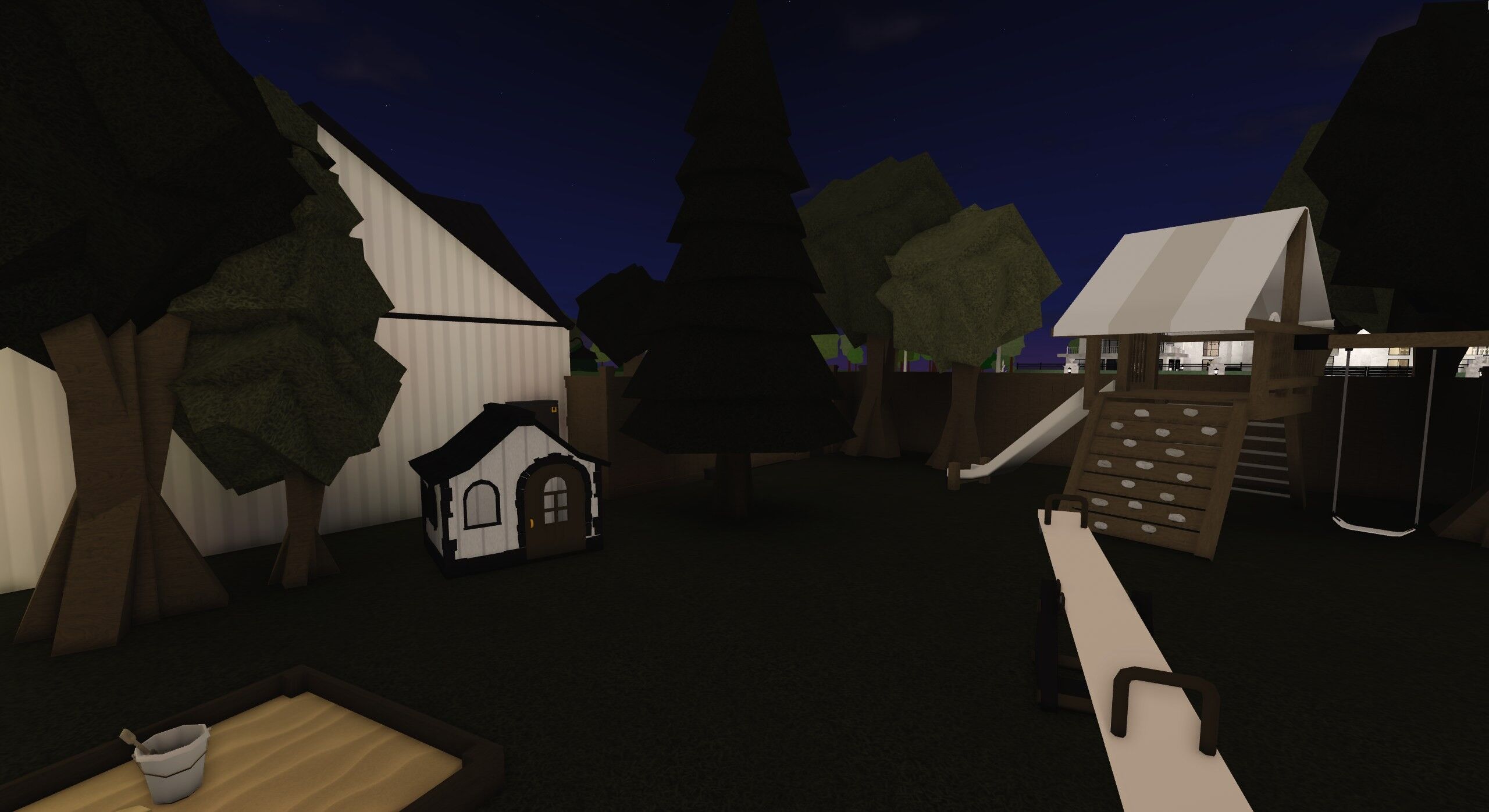 A fenced Bloxburg back garden at night with a wooden playset with a slide and climbing wall, a swing, a seesaw, a sandbox and a small playhouse